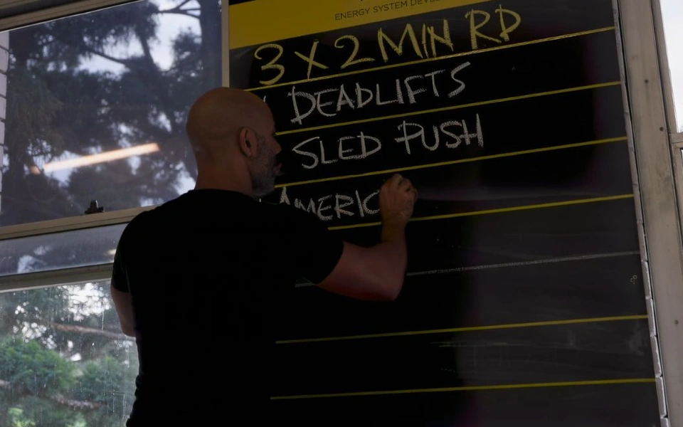 Soultrain coach preparing the training plan on a black and yellow workout board